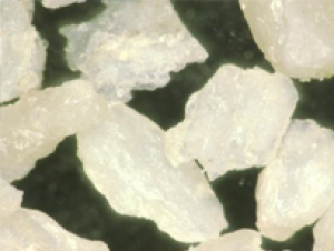 Macro close-up of dense, angular off-white bone particulate chips against a dark background.