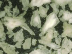 Macro close-up of thin, irregular flaky white bone particulate chips against a dark background.