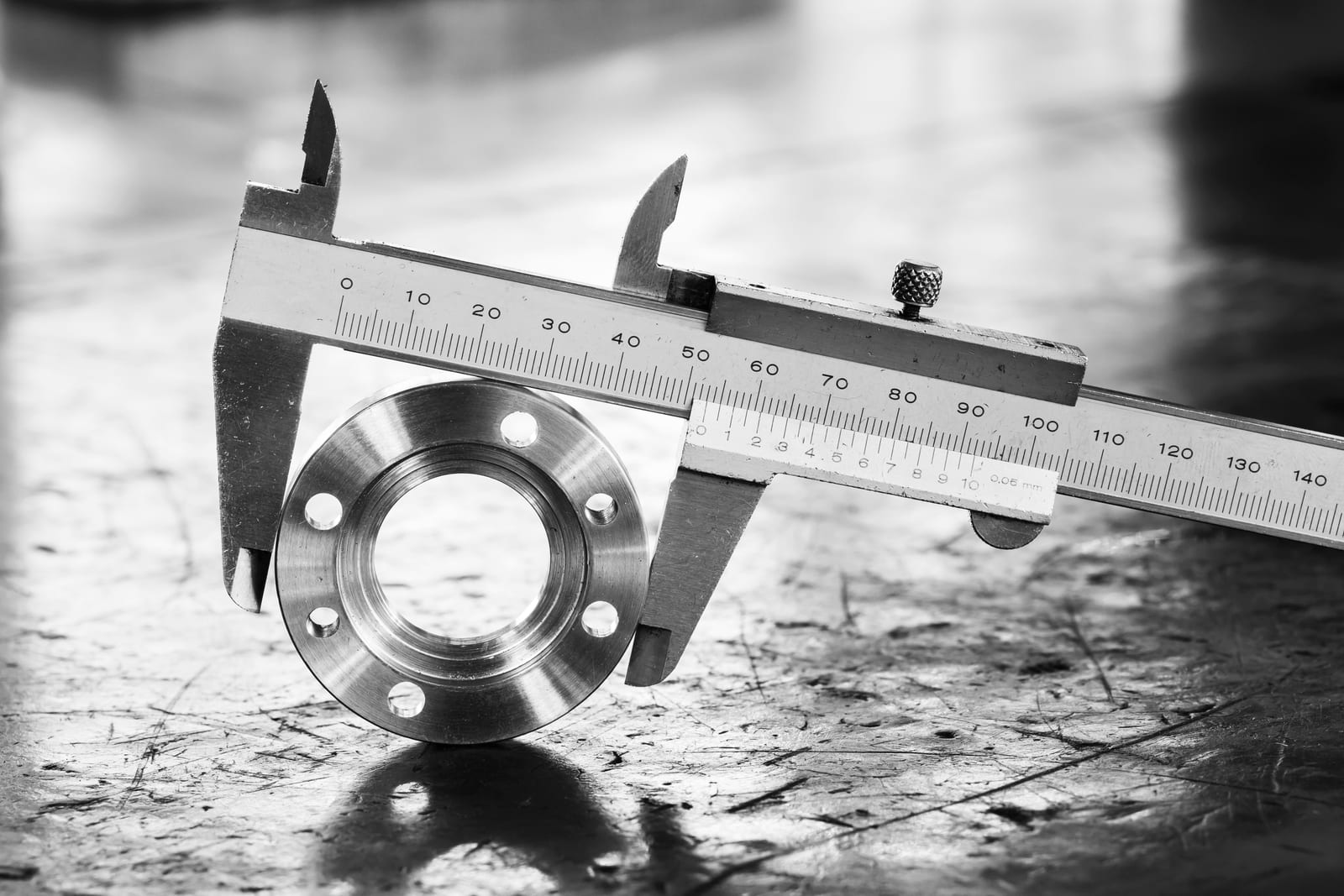 A vernier caliper precisely measuring a machined metal flange, illustrating the manufacturing tolerances behind hardware quality